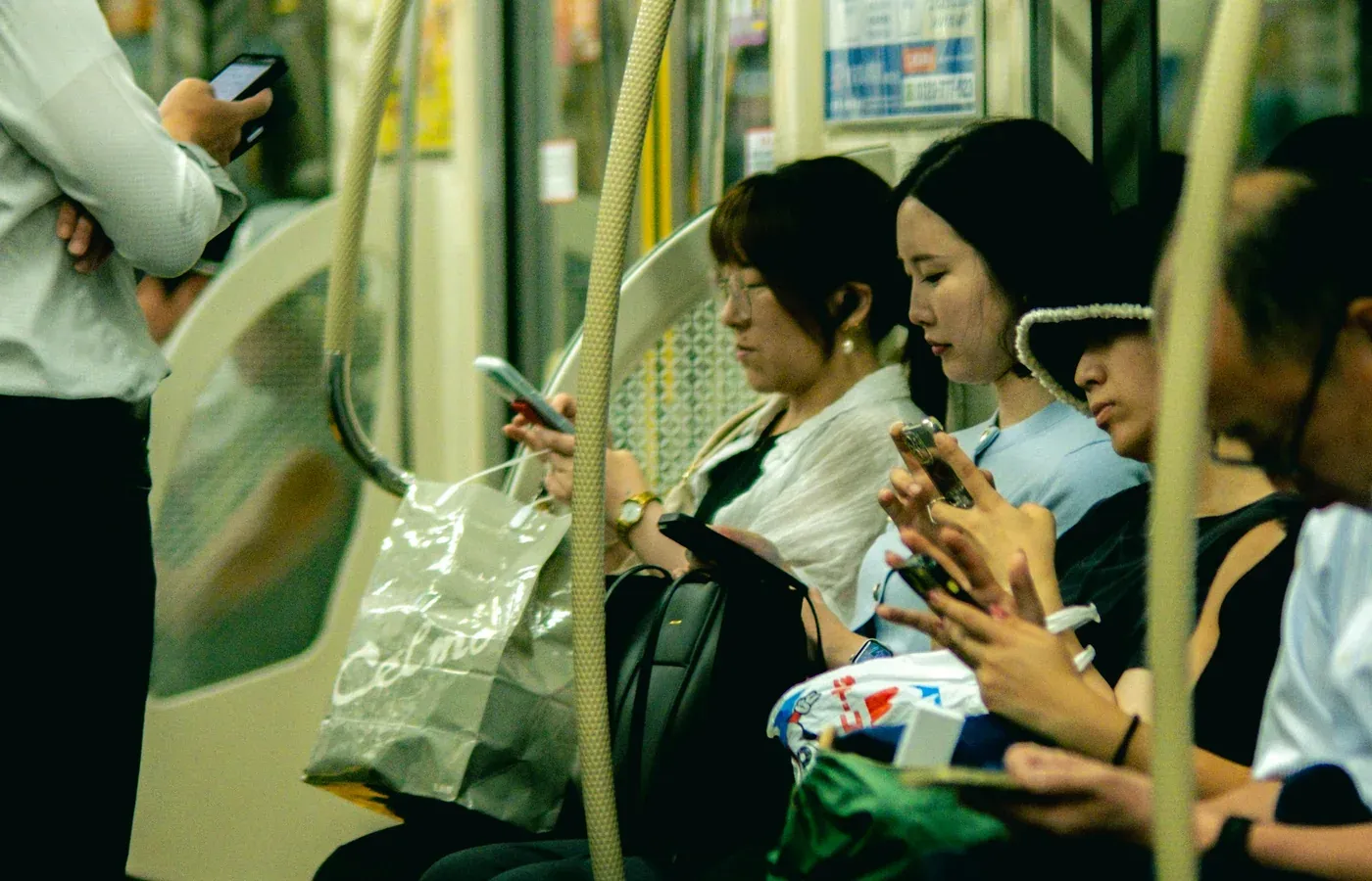 Những hành khách cùng nhìn vào điện thoại trên một chuyến tàu